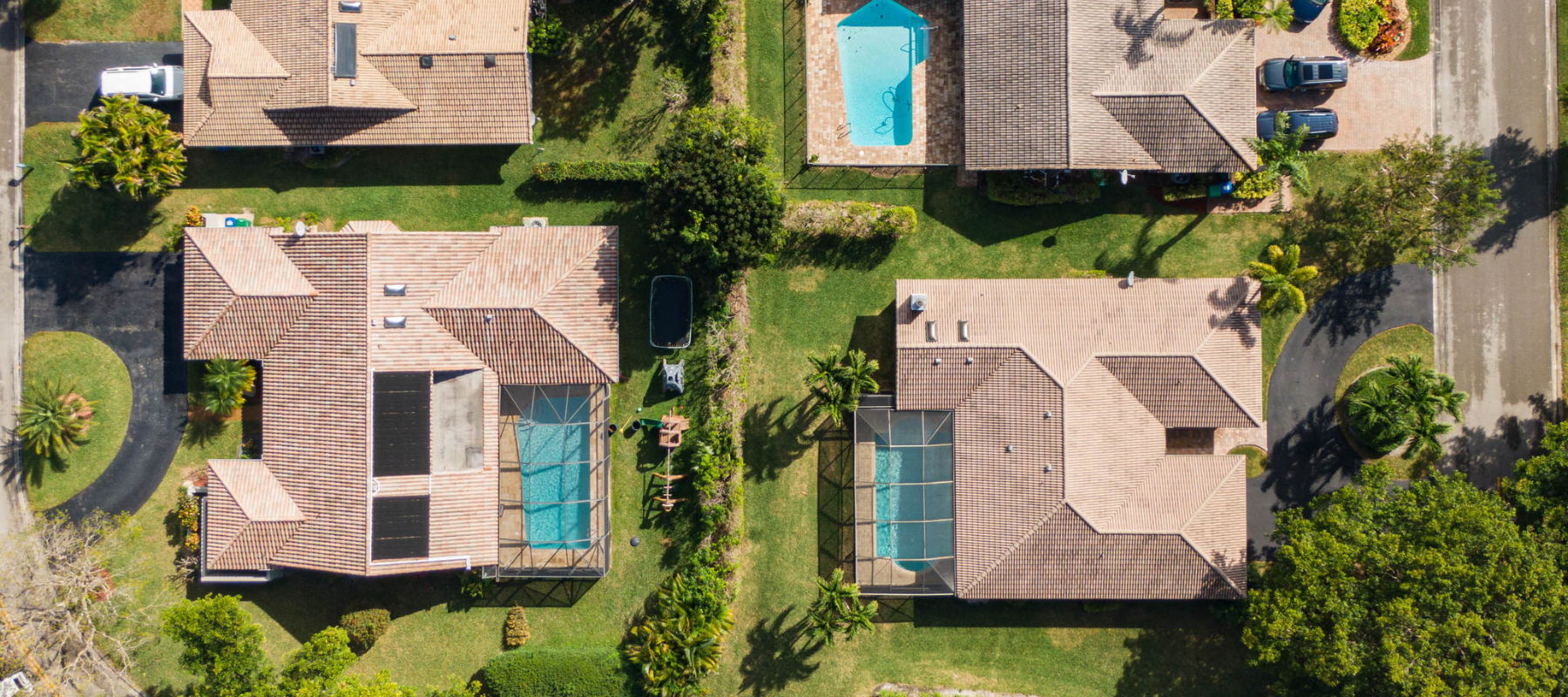 Aerial view of two homes with screened-in pools and lush green landscaping